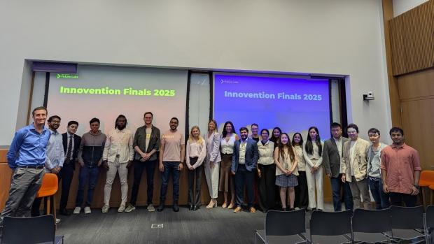 Large group of students posed in front of two screens that read "Innovention finals 2025"