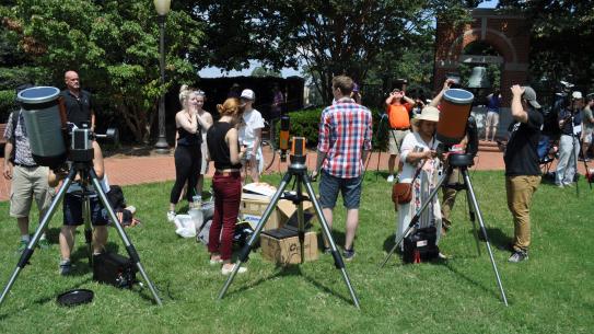 students with telescopes on a lawn