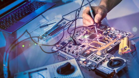 a hand holding a toll working on an electric board