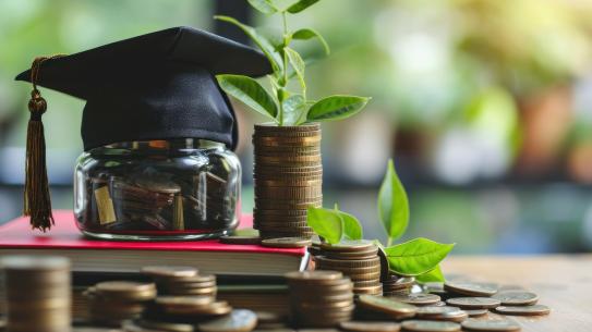 Money jar with a graduation hat, lots of coins