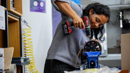 student using a drill in the makerspace