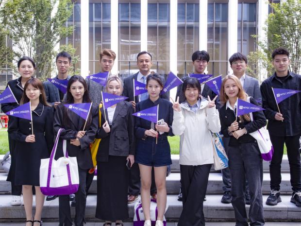 NYU Shanghai Students holding NYU pennants