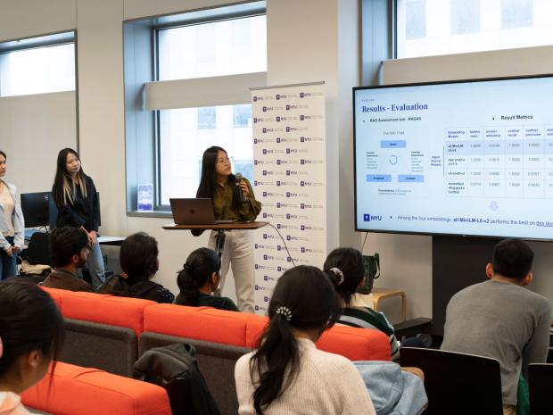 Three students to the left of a screen that reads "Results and Evaluation" in front of a seated audience.