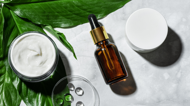 A cream, serum and jar on top of a leaf