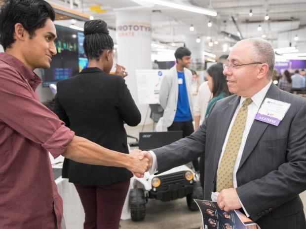 student shaking hand with an alum student shaking hand with an alum