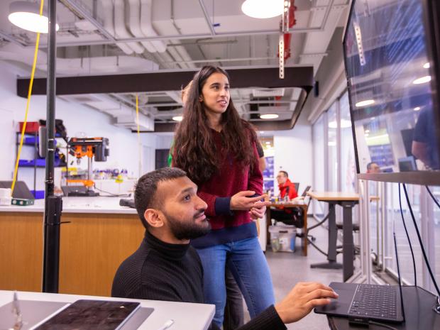 a male and female student looking at computer equipment in a lab