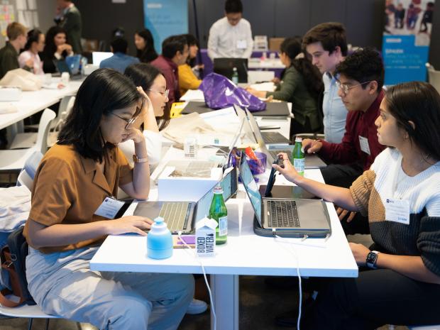 students working on laptops at large table