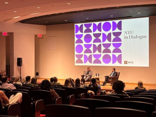 Two people in conversation on stage with an audience