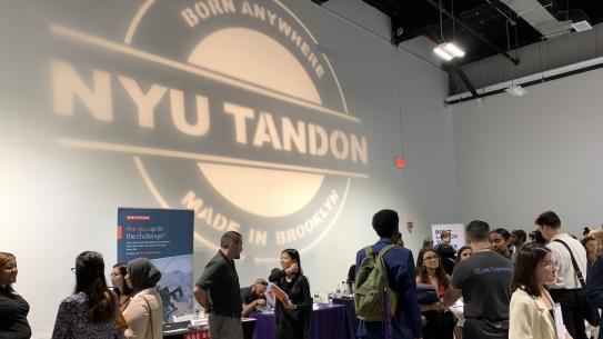 2019 NYU Tandon Career Fair Large Tandon logo projected on wall at crowded career fair